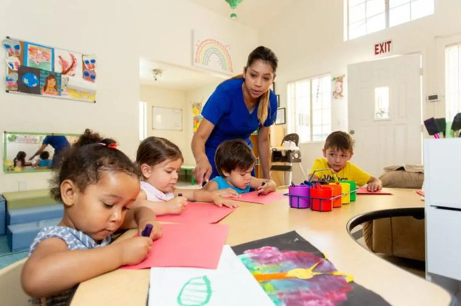 Upwards teacher helps children with art Upwards childcare provider Tanya Garcia works with children as they create artwork at daycare.