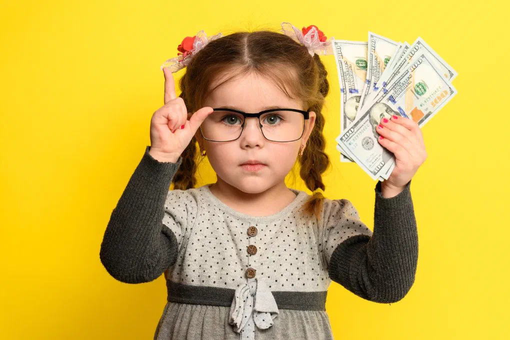 A toddler holding money, illustrating employer-sponsored childcare stipends